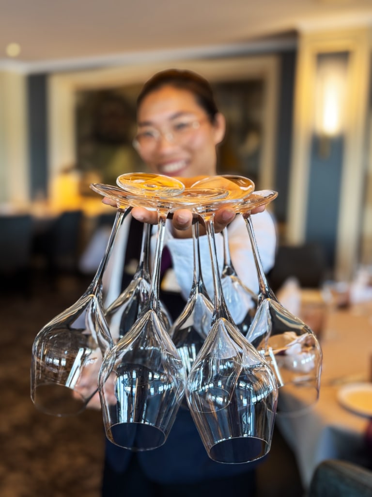 Waiter skillfully balancing wine glasses on a serving tray in a restaurant