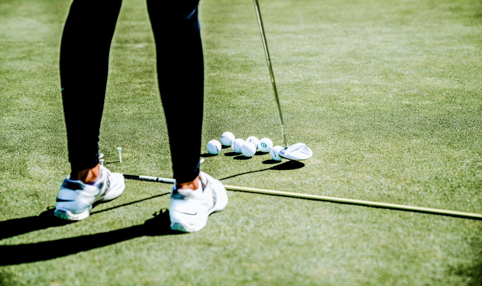 Golfspieler beim Üben mit mehreren Golfbällen auf dem Grün